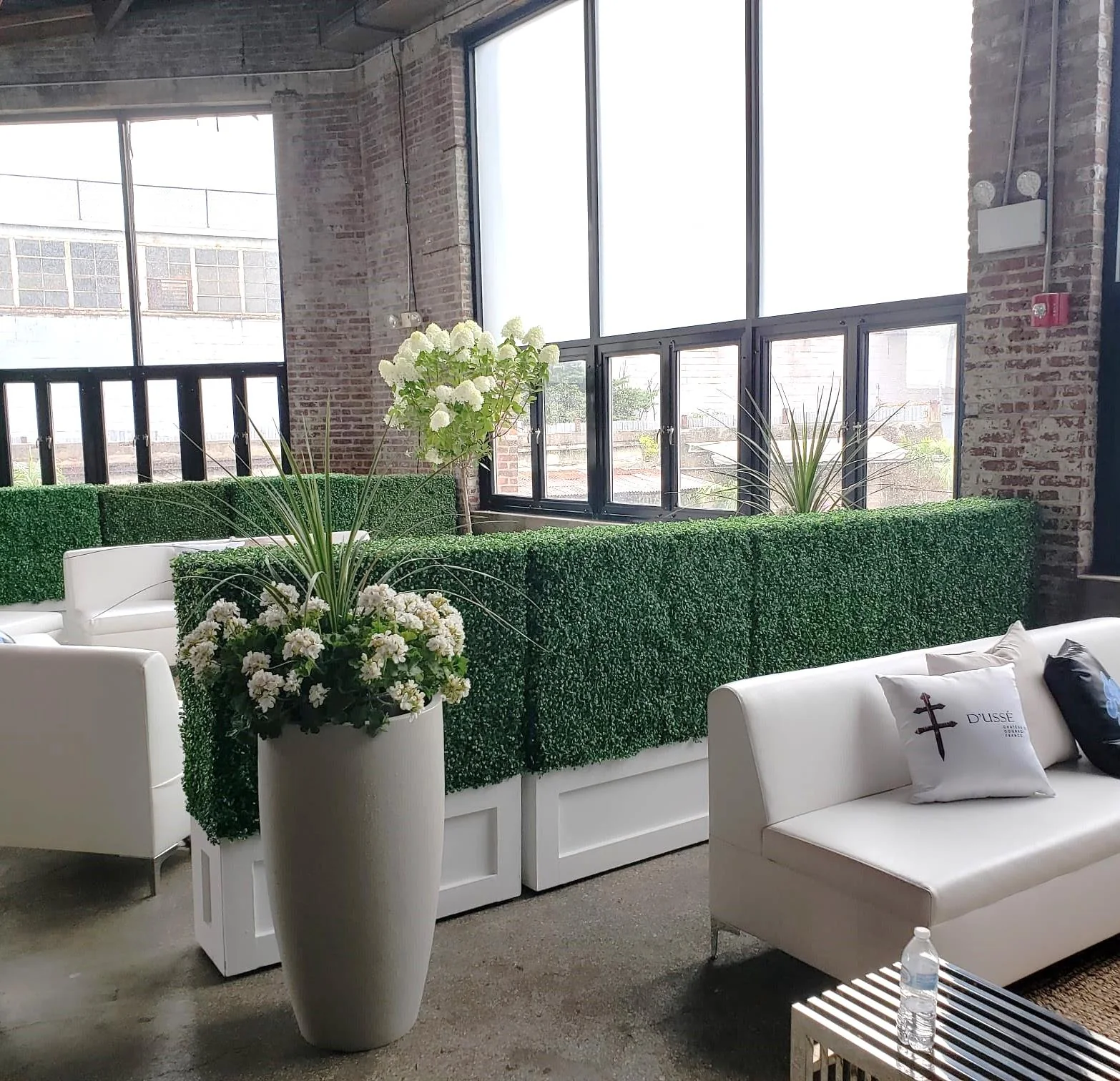 White orchids and greenery dividers beside lounge seating and tall windows.