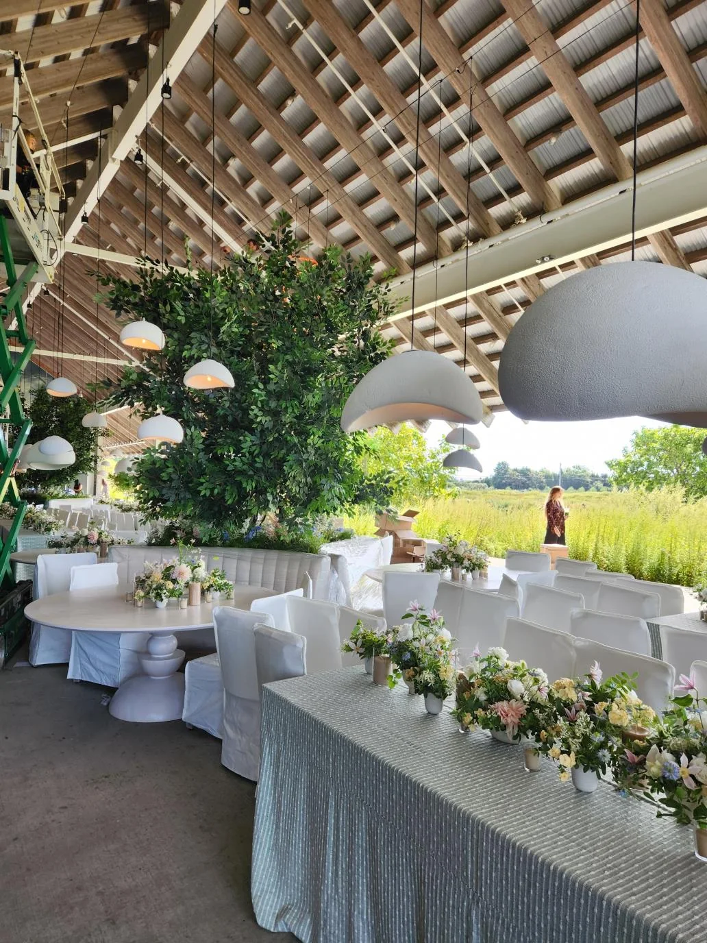 A reception beneath a timber roof, with hybrid trees rising among the tables.